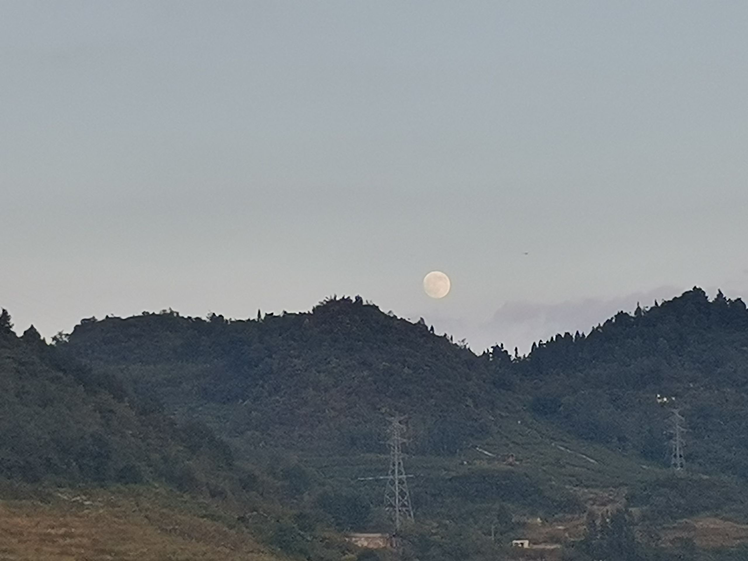 中秋山脊上的满月与输电铁塔